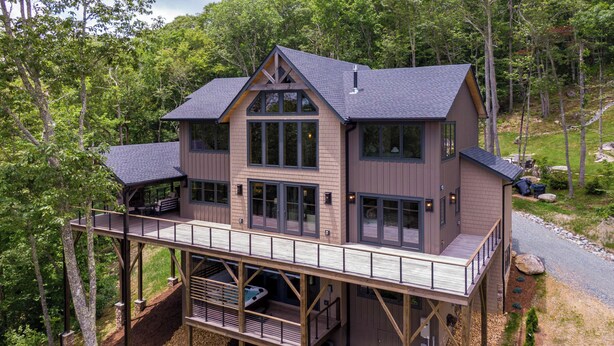A multi-story wooden cabin with a deck, surrounded by forest. - Ambience Lodge at Eagles Nest (Banner Elk)