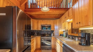 A kitchen with wooden cabinets, stainless steel appliances, and a built-in oven. - Whispering Ridge Retreat (Boone)