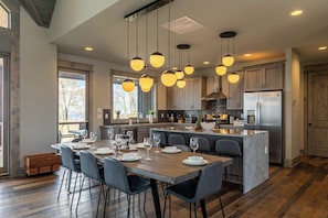 A modern kitchen with a central island, wooden cabinets, and pendant lighting. - Zion at Eagles Nest (Banner Elk)