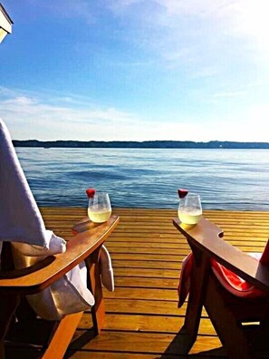 A wooden deck with two tables, each with a glass of white wine and a red napkin.
