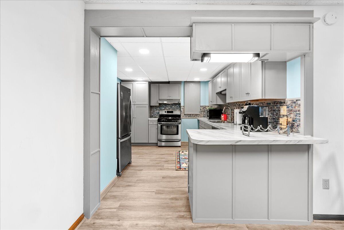A modern kitchen with grey cabinets, a central island, and a tiled backsplash.