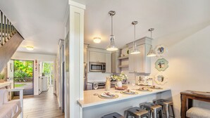 A modern kitchen with stainless steel appliances, a central island with bar stools, and pendant lighting.
