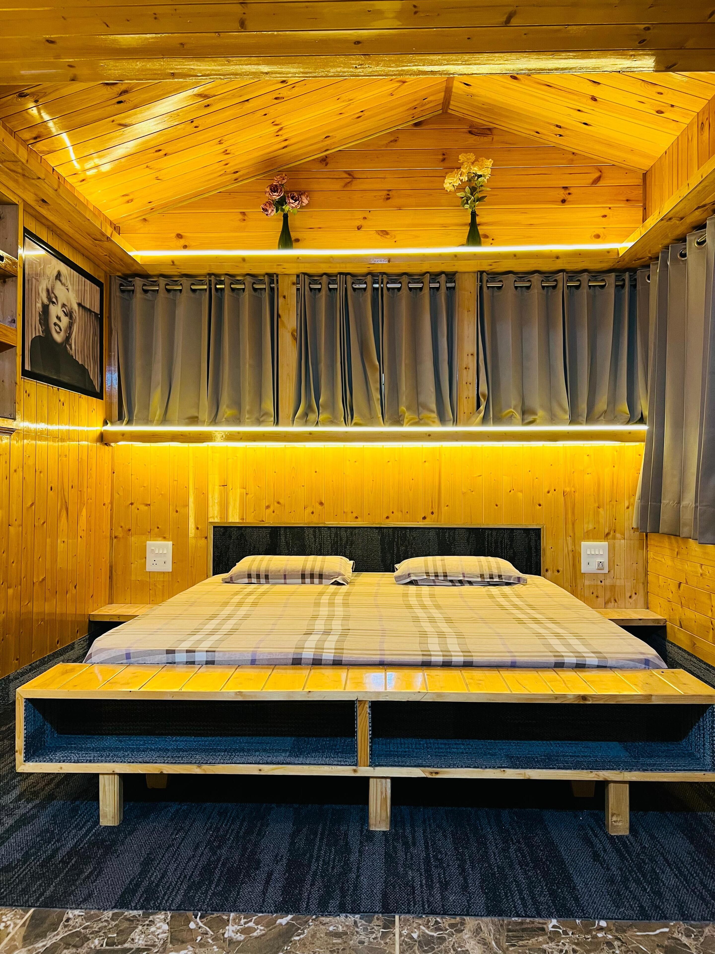 A wooden room with a bed, curtains, and a framed picture on the wall.
