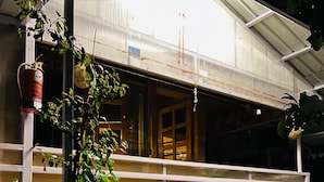 A covered outdoor area with potted plants and a metal staircase. - Snooze Cottage (Dhari)