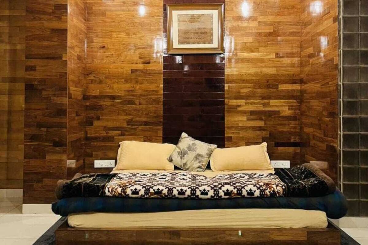 Une chambre moderne avec un mur d’accent en bois, un tableau encadré et un lit avec une literie à motifs.