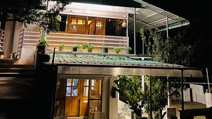 A two-story house with a covered porch and potted plants. - Snooze Cottage (Dhari)