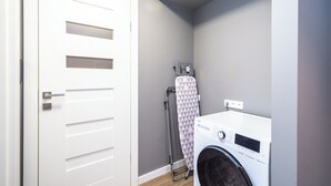 A laundry room with a washing machine, a drying rack, and a door. - RentPlanet - Apartament Kasztelańska (Kraków)