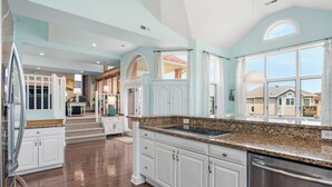 A spacious kitchen with white cabinetry, granite countertops, and a stainless steel dishwasher. - Tickled Pink: Pool | Hot Tub | Elevator | Dogs OK (Corolla)
