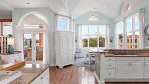 A spacious kitchen with white cabinetry, a granite countertop, and a view of the outside. - Tickled Pink: Pool | Hot Tub | Elevator | Dogs OK (Corolla)