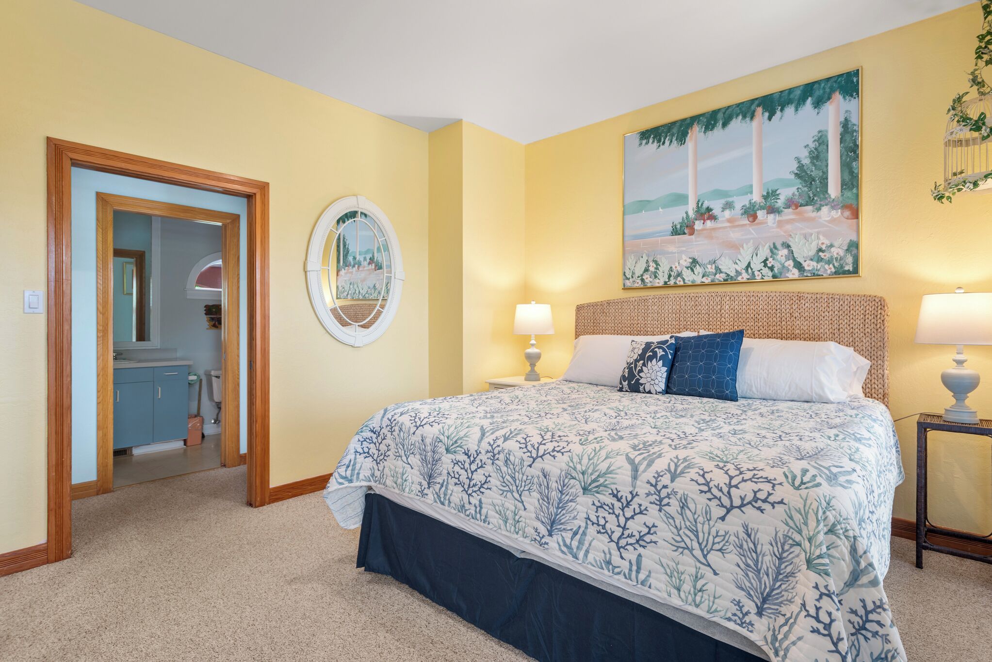 A bedroom with a bed, two bedside tables, a mirror, and a painting on the wall.