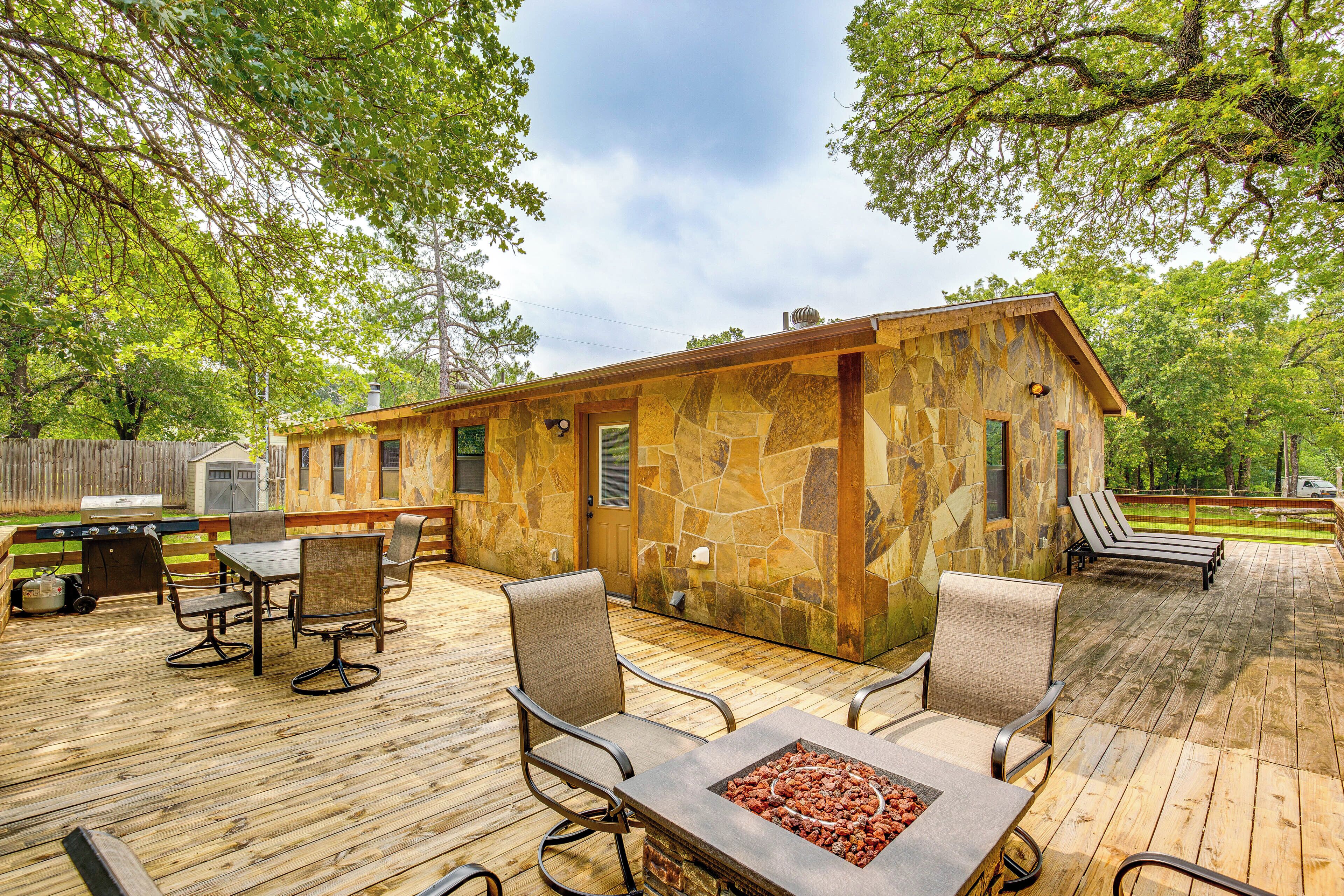 A stone cabin with a deck, outdoor seating, and a fire pit.