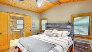 A bedroom with a wooden ceiling, a bed with striped bedding, a nightstand, and a window with blinds. - Deck & Fire Pit: Unique Pottsboro Haven (Pottsboro)