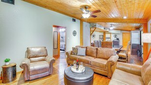A spacious living room with leather sofas, a coffee table, and a ceiling fan. - Deck & Fire Pit: Unique Pottsboro Haven (Pottsboro)