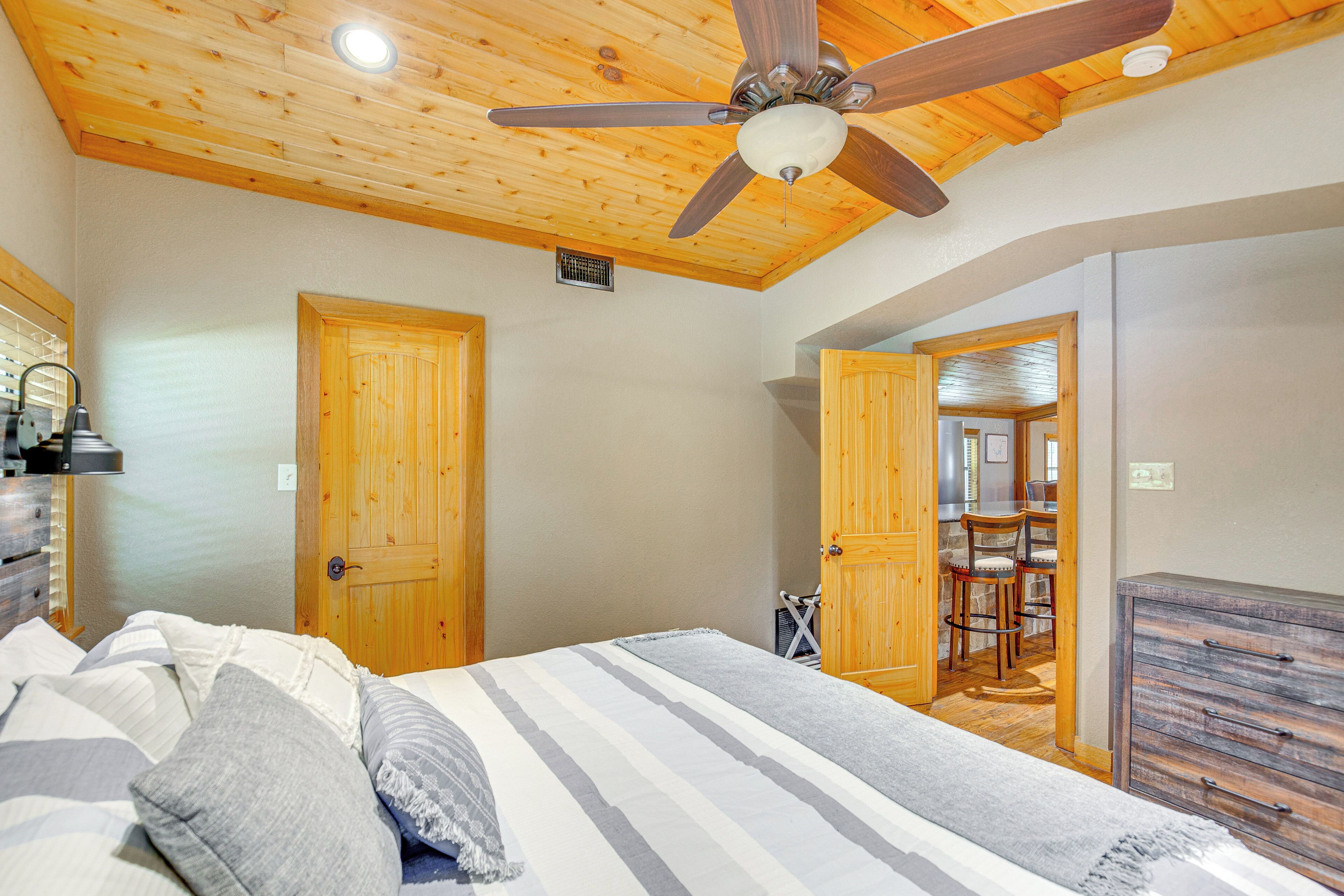 A bedroom with a bed, wooden ceiling, and a ceiling fan.