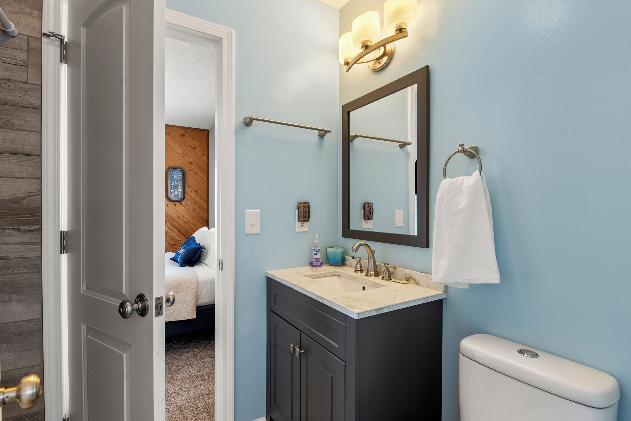 A bathroom with a sink, mirror, towel rack, and toilet.