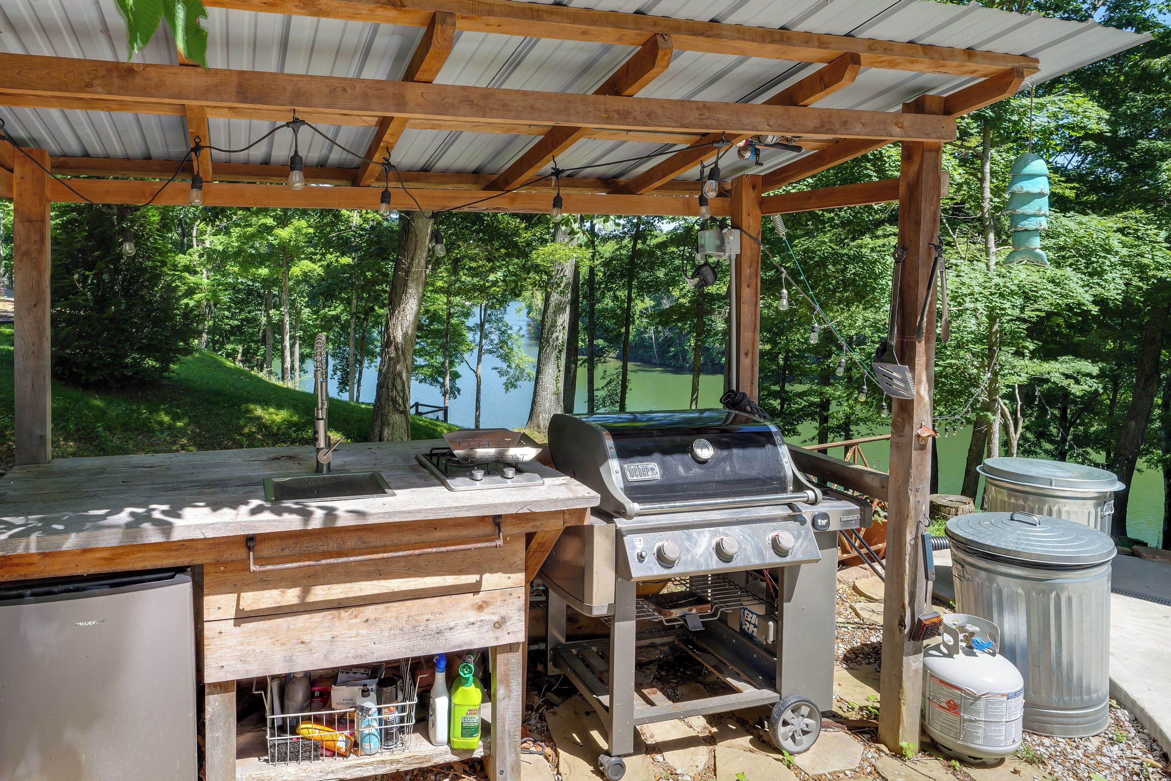 An outdoor barbecue area with a grill, sink, and storage cabinets.