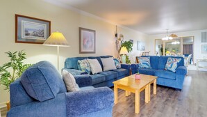 Un salon avec deux canapés bleus, une table basse en bois et une lampe.