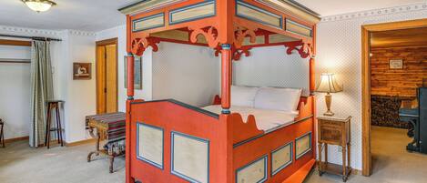 Un lit à baldaquin avec une structure en bois et un ciel de lit, une table de chevet avec une lampe, et un tapis à motifs.