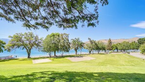Un parcours de golf offrant une vue dégagée sur l’eau et les collines en arrière-plan.