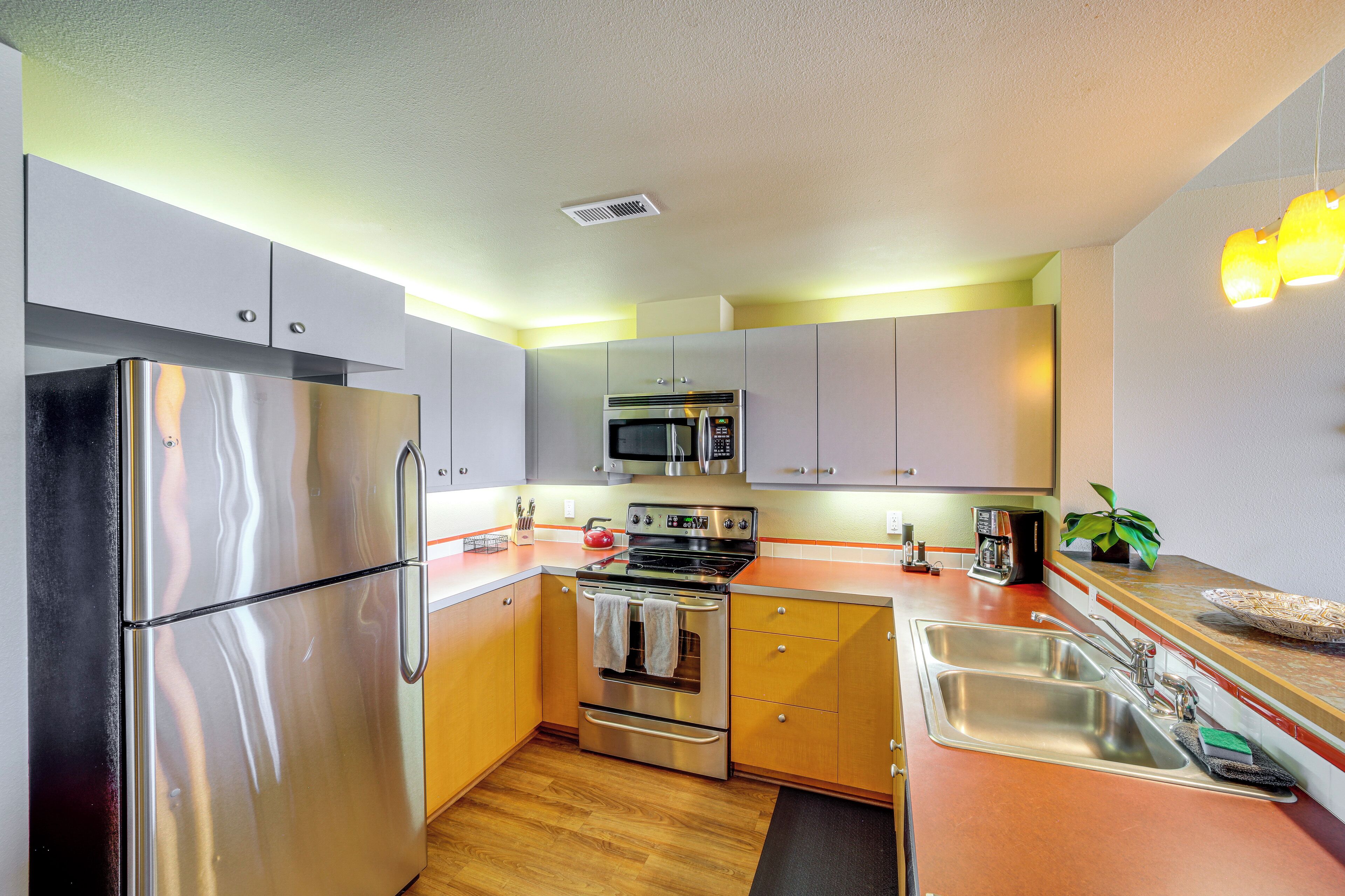 A modern kitchen with stainless steel appliances, wooden cabinets, and a granite countertop.