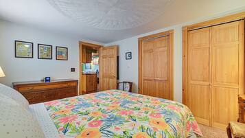 A bedroom with a floral bedspread, wooden wardrobe, and a ceiling fan.