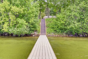 A wooden bridge leading to a building surrounded by dense green foliage. - Spacious Detroit Lakes Home w/ Private Deck! (Detroit Lakes)