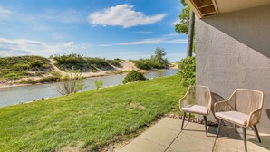 Un patio con dos sillas de mimbre que da a un río y una zona de césped.