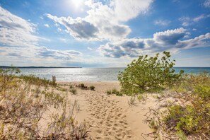 A sandy beach with a clear sky and a distant view of the sea. - Glen Arbor Riverfront Retreat: Steps to Beach! (Glen Arbor)