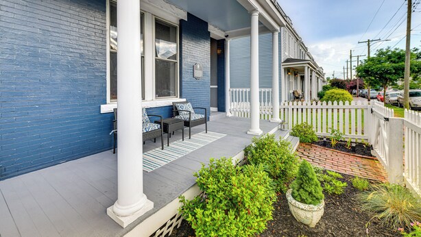 Ein blaues Haus mit Veranda, weißen Säulen und einem weißen Zaun.