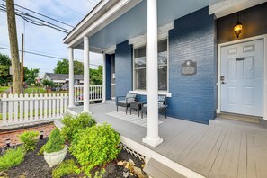 Ein blaues Haus mit einer Veranda, weißen Säulen und einer weißen Tür.