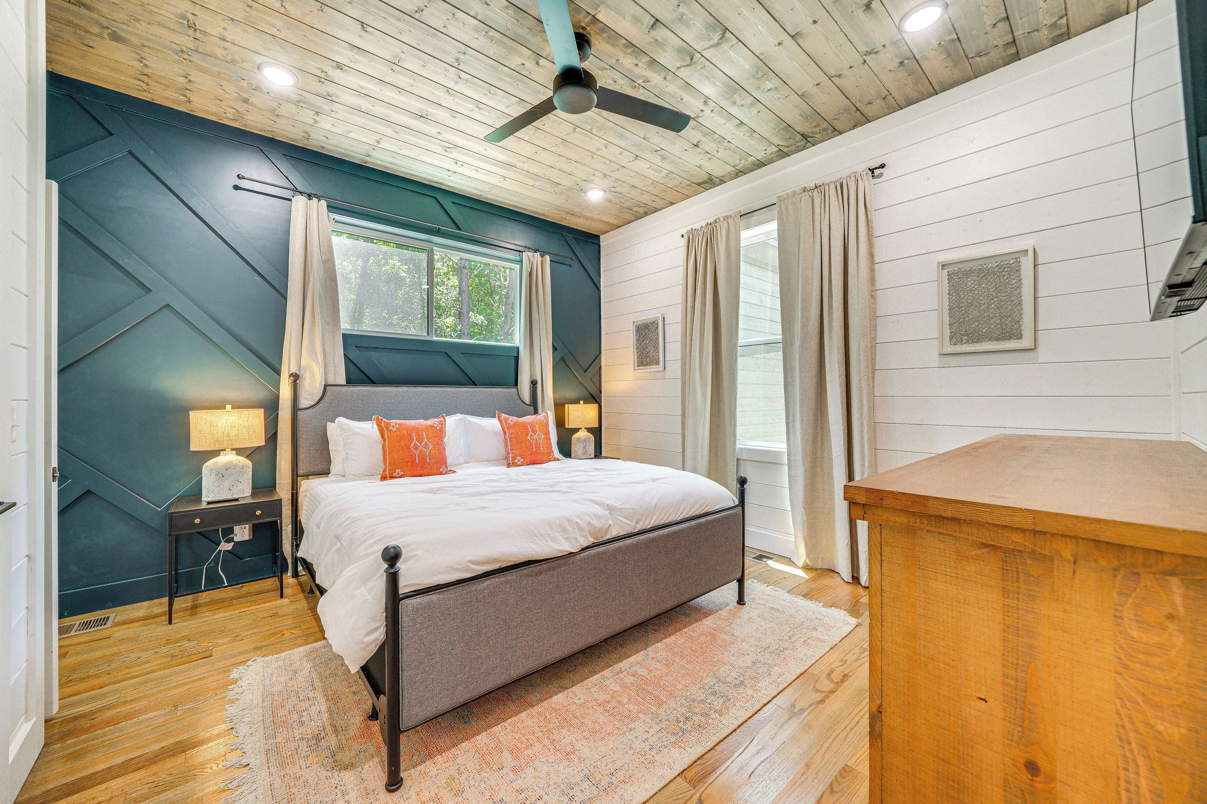 Quarto com cama, piso de madeira, ventilador de teto e mesa de cabeceira com abajur.
