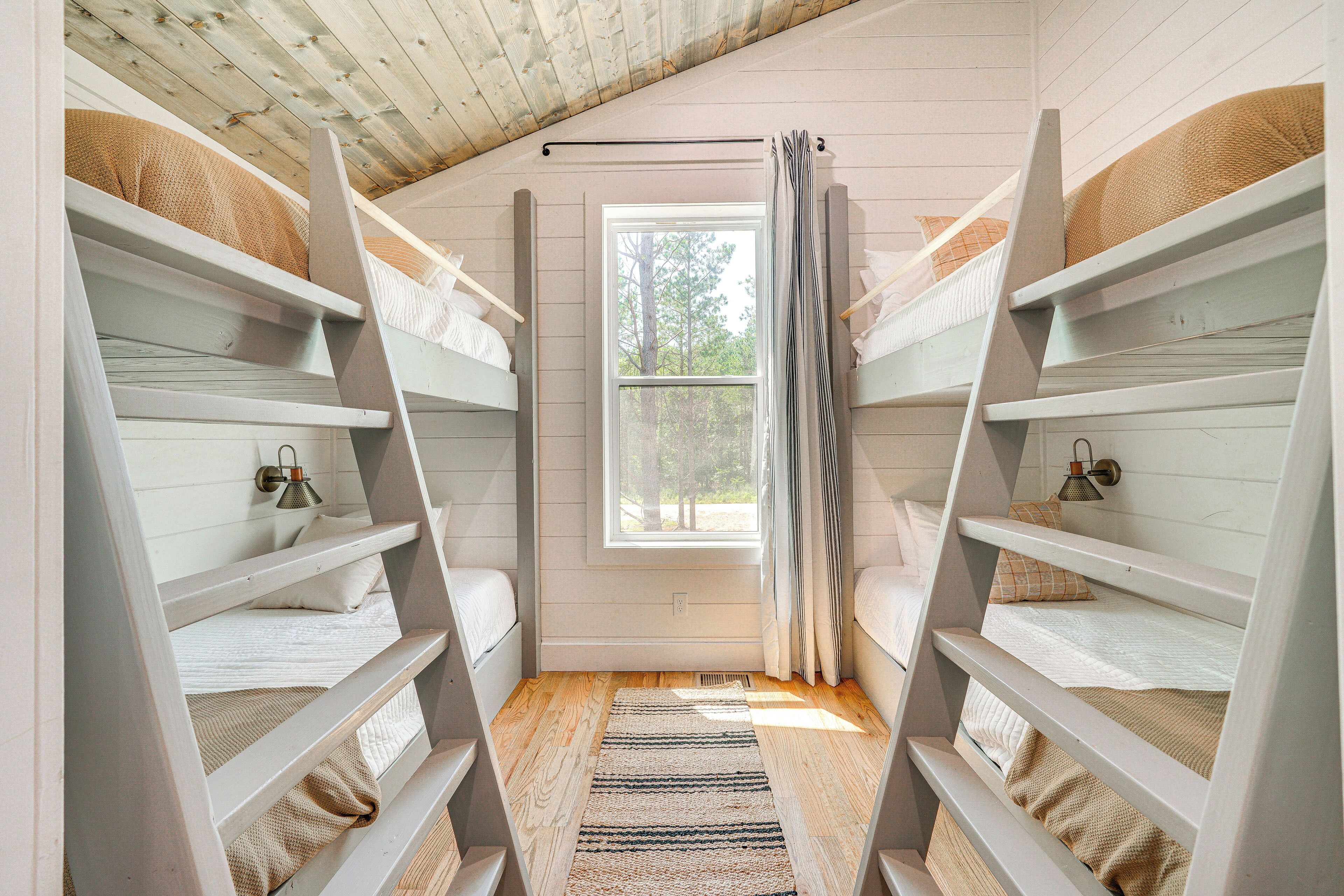 A room with bunk beds, a window, and a wooden ceiling.