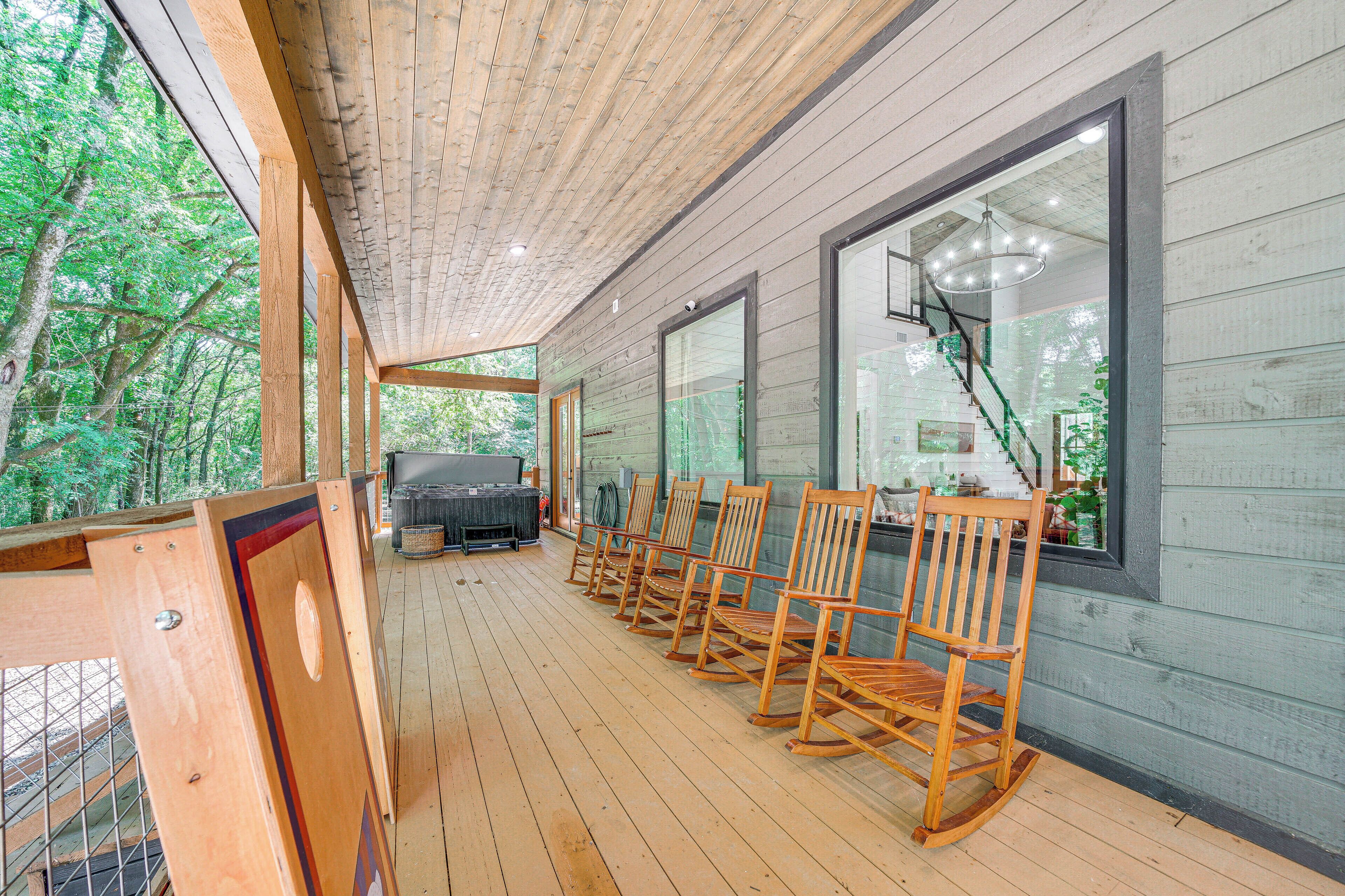 A wooden deck with rocking chairs and a barbecue grill, overlooking a forested area.