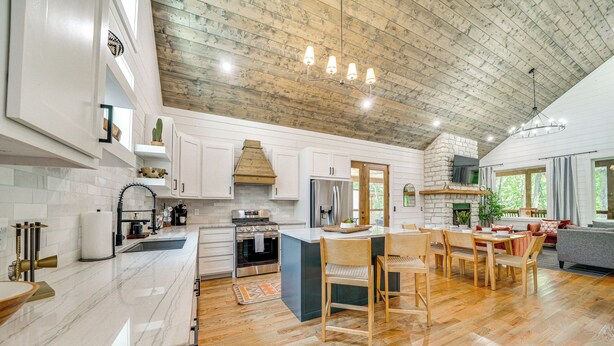 Une cuisine spacieuse dotée d’un plancher en bois, de meubles blancs et d’un grand îlot central.