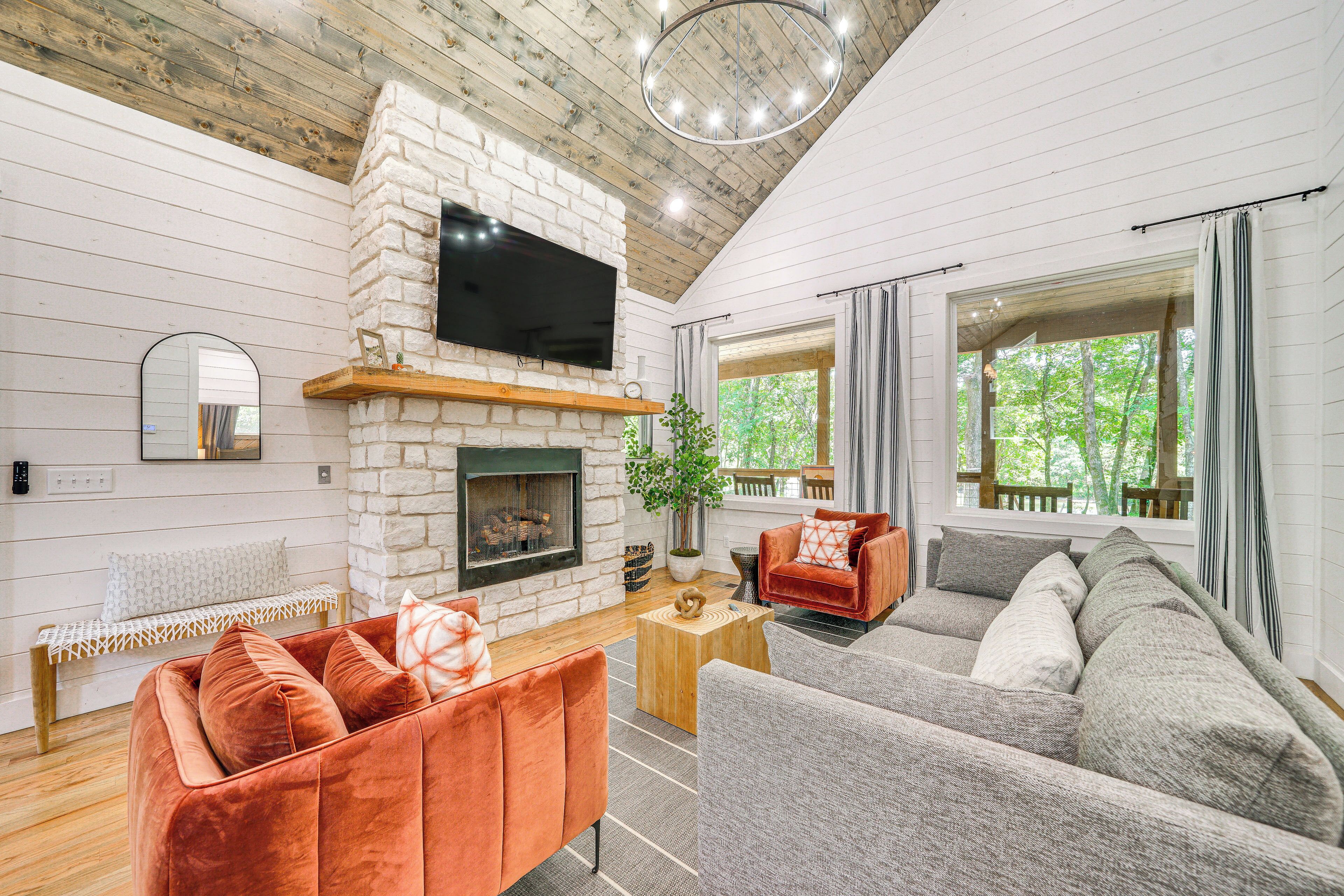 A cozy living room with a stone fireplace, a large flat-screen TV, and a comfortable seating area with a sofa and armchairs.