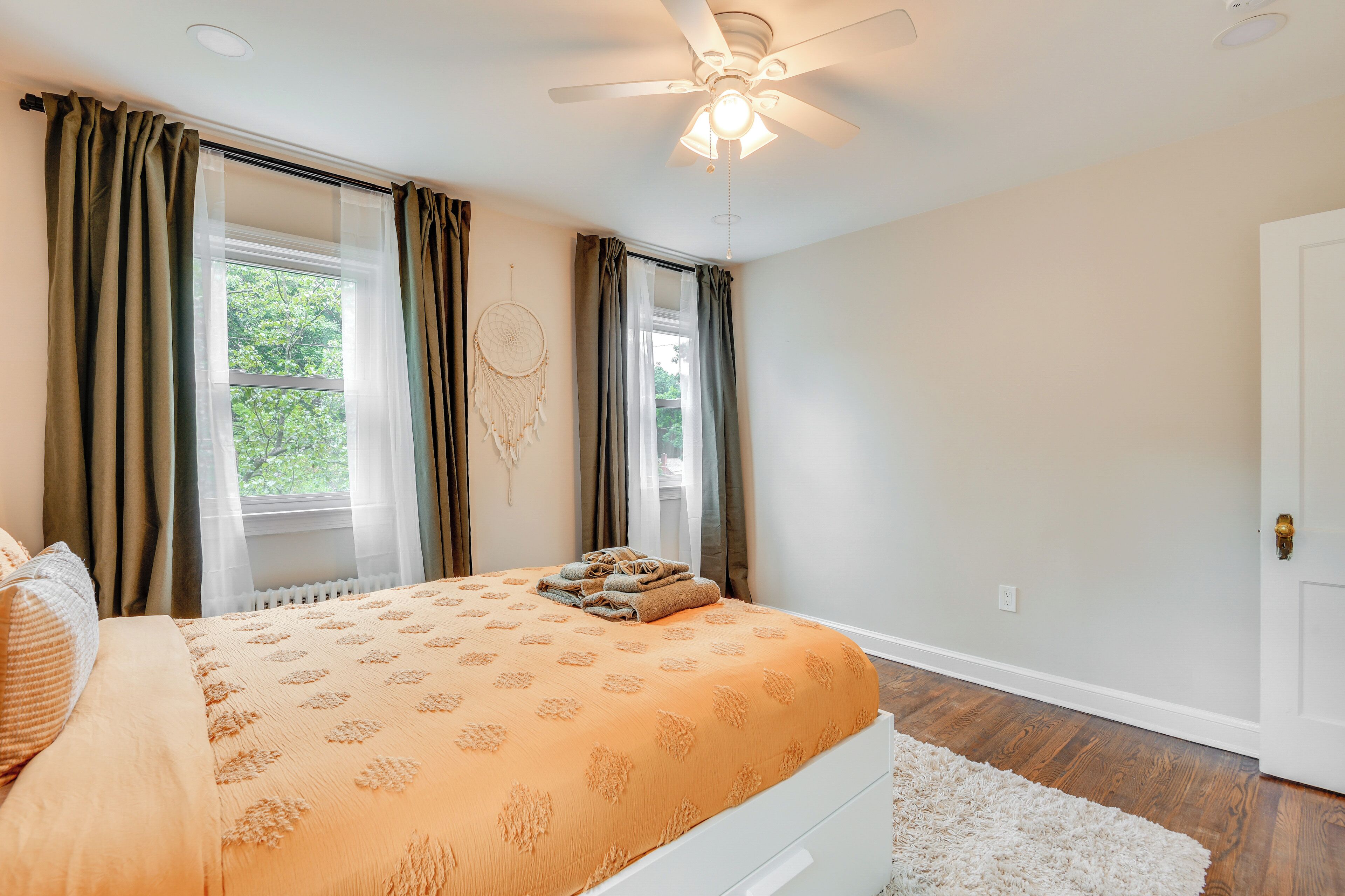 A bedroom with a bed, a ceiling fan, and a window with curtains.