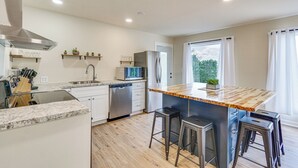 A modern kitchen with a central island, stainless steel appliances, and bar stools. - Kayaks, Boat Slip, Game Room, Calm Cove, Great Loc (Osage Beach)