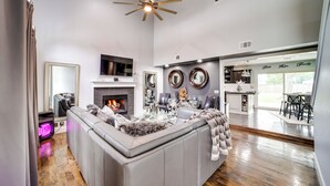 A spacious living room with a large L-shaped gray sofa, a fireplace, and a ceiling fan. - 'peace & Tranquility': Home 2 Mi to Dtwn Tulsa! (Tulsa)