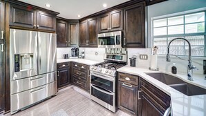 A modern kitchen with dark wood cabinets, stainless steel appliances, and a large window providing natural light. - 'peace & Tranquility': Home 2 Mi to Dtwn Tulsa! (Tulsa)