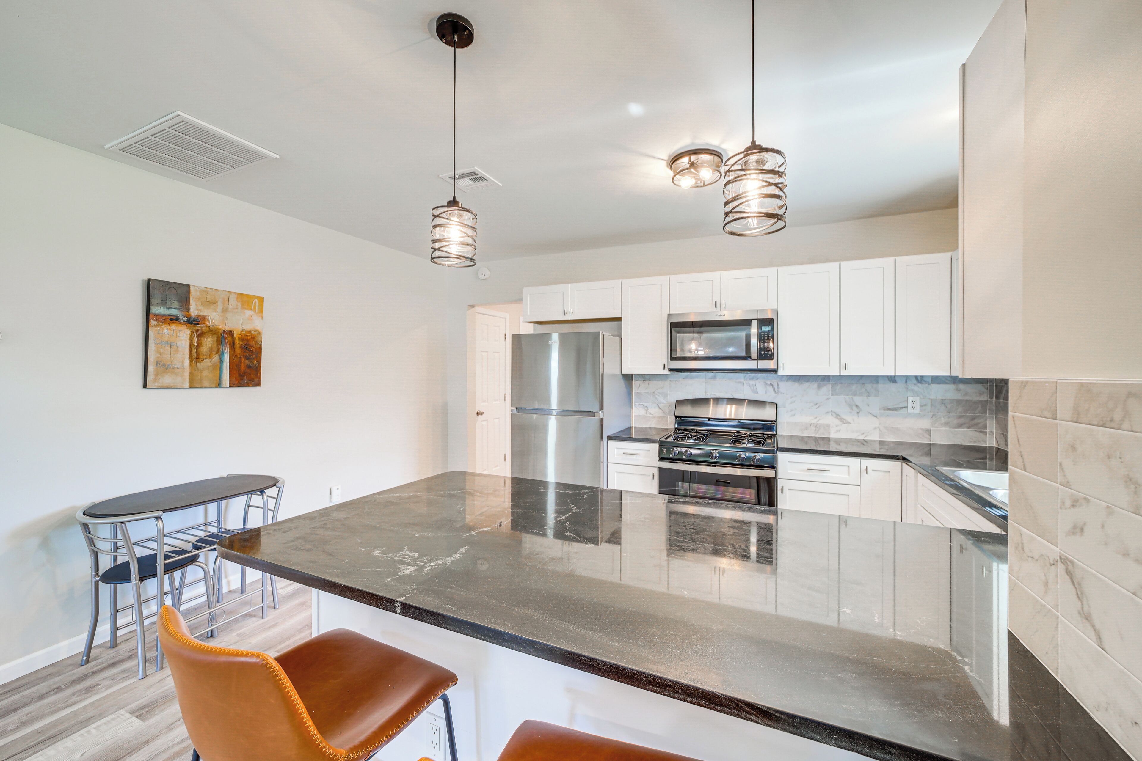 A modern kitchen with a central island, stainless steel appliances, and pendant lighting.