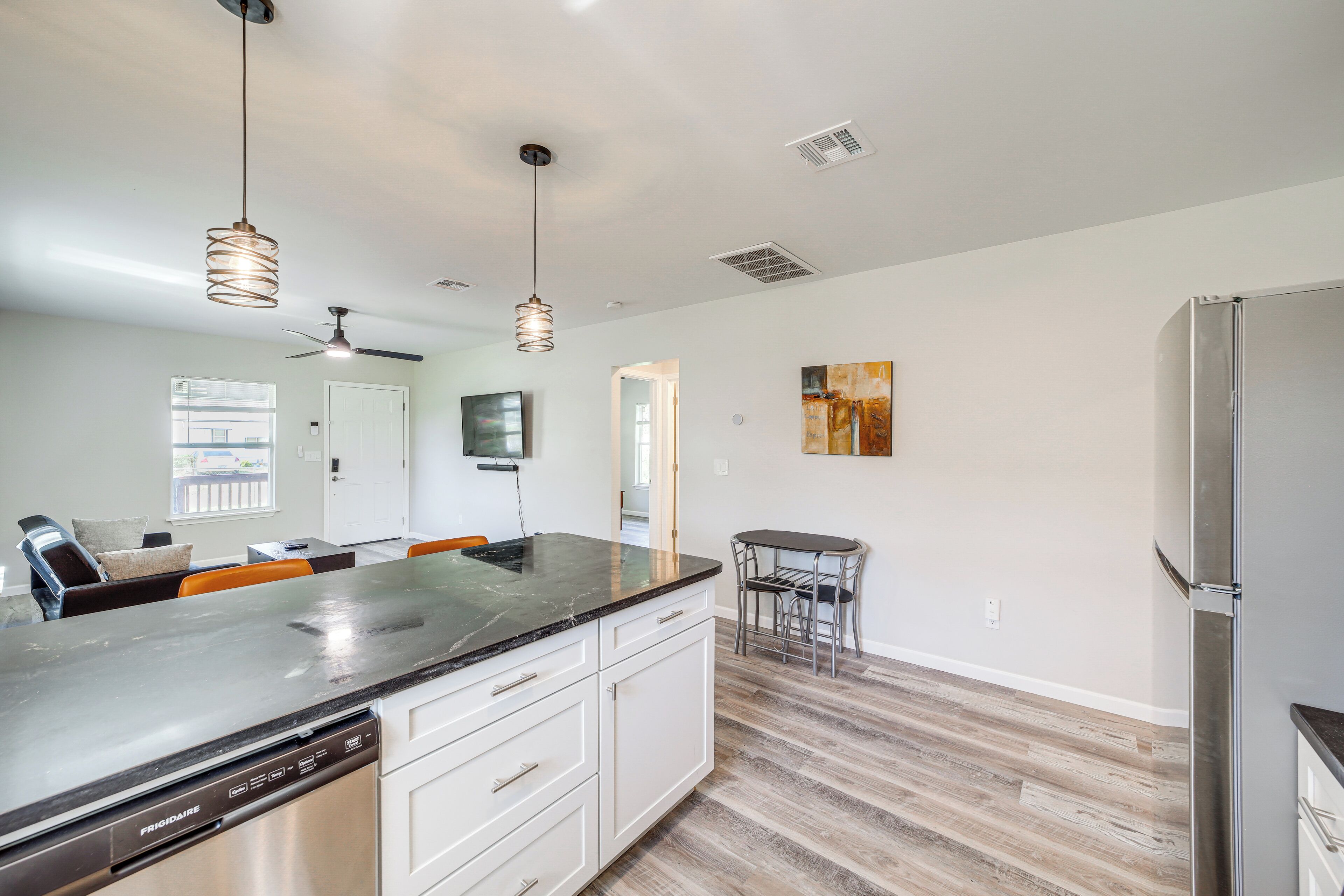 A modern kitchen with a dishwasher, a refrigerator, and a dining area with a table and chairs.