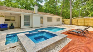 Um quintal com piscina, deck de madeira e varanda coberta.