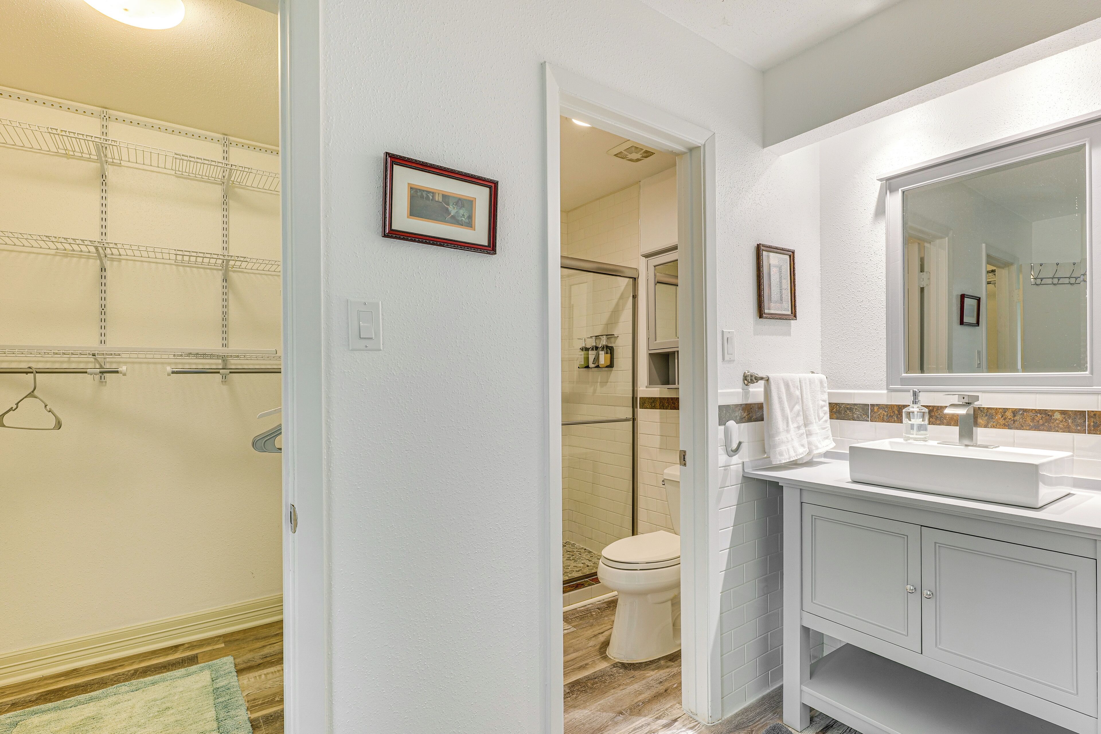 A bathroom with a white vanity, a large mirror, and a shower area visible through an open door.
