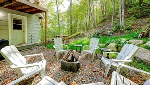 Eine Hütte mit Außenbereich, Sitzgelegenheiten und einem Feuerkorb, umgeben von Bäumen.