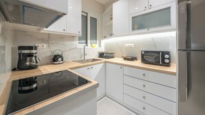 Una cocina moderna con armarios blancos, horno integrado, microondas y refrigerador.