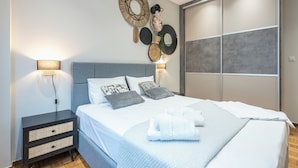 Un dormitorio moderno con una cama grande, mesitas de noche, decoración en la pared y un armario corredero.