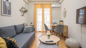 Una sala de estar moderna con un sofá gris, una mesa redonda de centro y un comedor con una mesa y sillas de madera.