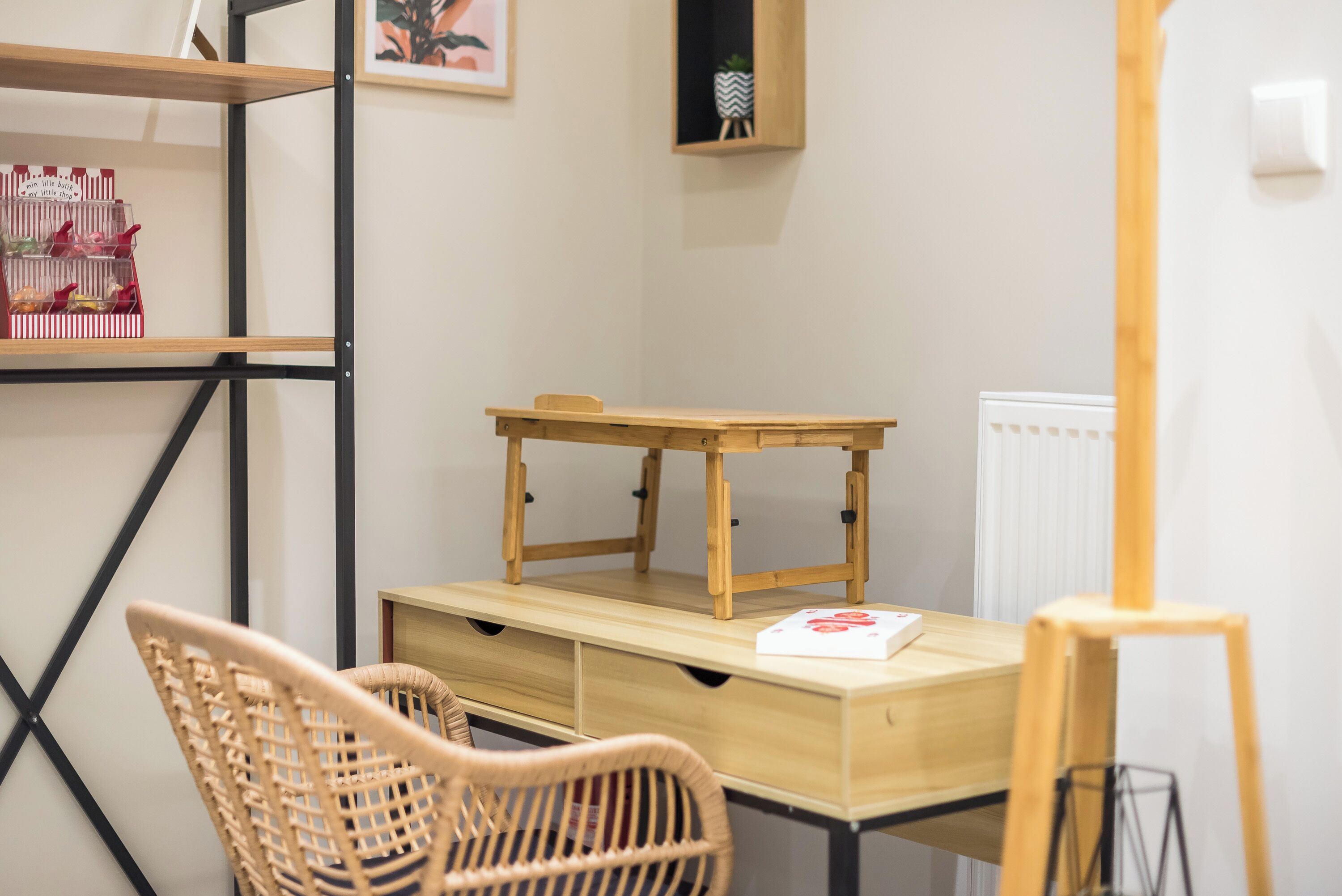 Une pièce avec un bureau en bois, des chaises en osier et un radiateur.