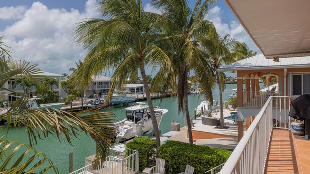 A marina with boats, palm trees, and a pool area. - Large home with a private pool! (Key Colony Beach)