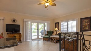 A spacious living area with a television, wicker furniture, and a ceiling fan. - Large home with a private pool! (Key Colony Beach)